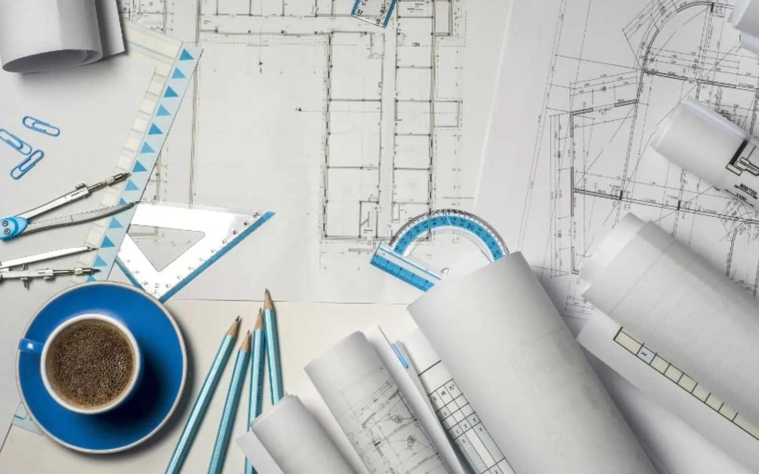 EMshield GmbH – Architektur und Unternehmenssicherheit – Dieses Bild zeigt den Arbeitsplatz eines Architekten oder Ingenieurs mit verschiedenen Zeichenwerkzeugen und technischen Dokumenten.